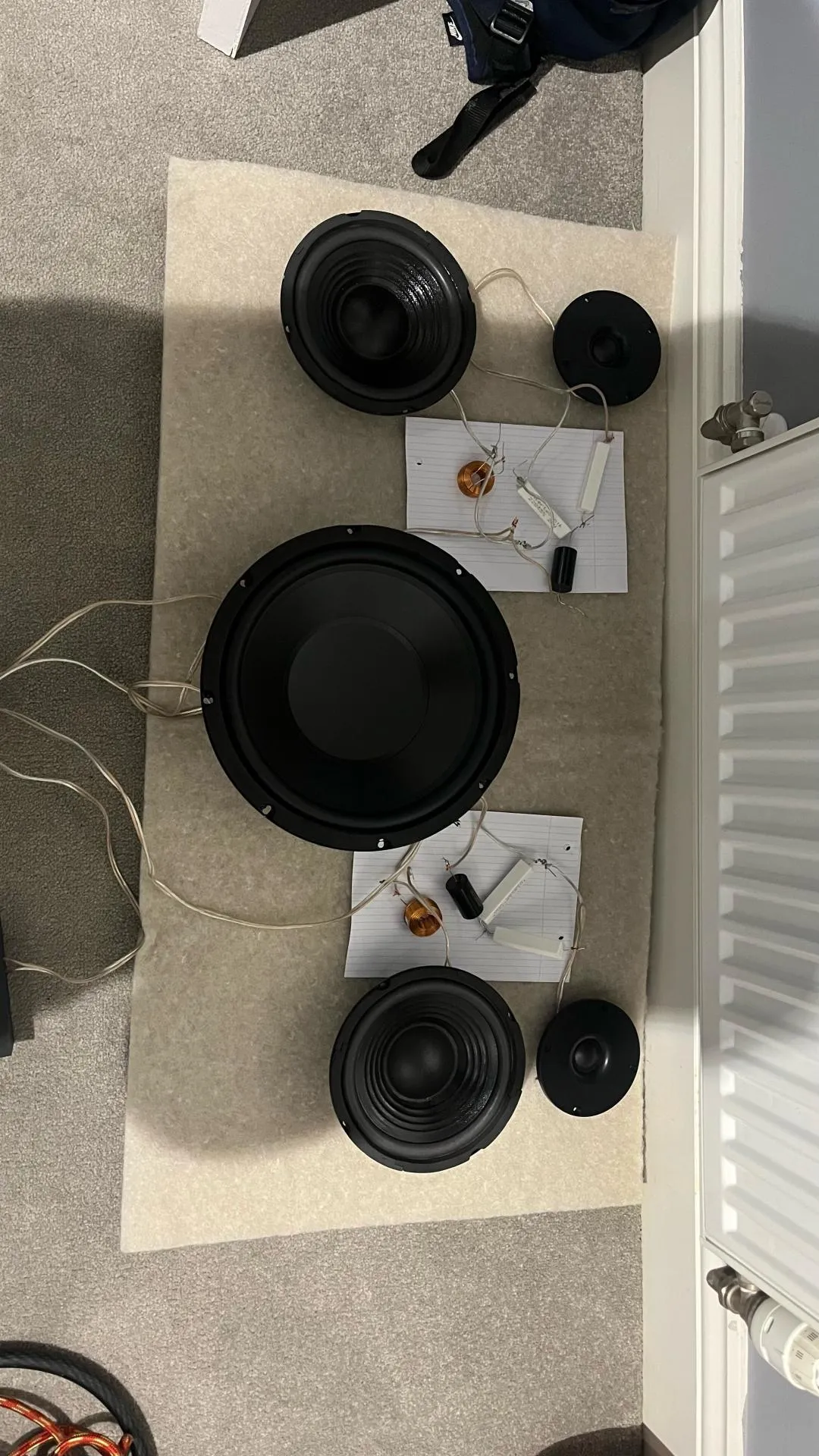 Subwoofer, midwoofers, tweeters and wired passive crossover parts laid out before enclosure assembly